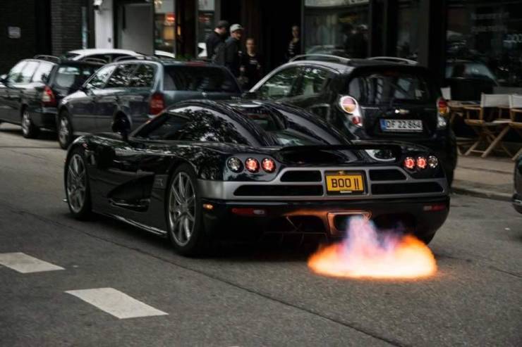 Koenigsegg accelerates on the road in the city and its exhaust pipe bursts into flames.