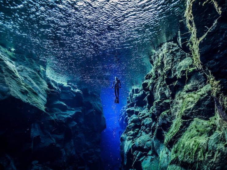 The diver goes under the water in the Silfra. This is a place in the sea, located between tectonic plates in Thingvellir National Park.