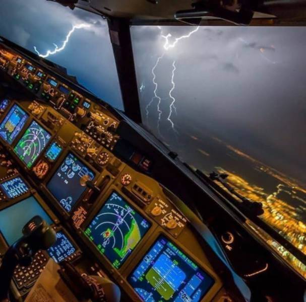 The plane flies by storm clouds. Flashes of lightning are visible from the cockpit.