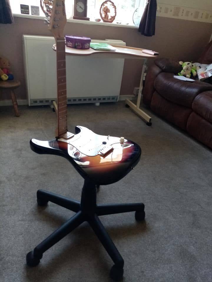 A chair on wheels made from an electric guitar.