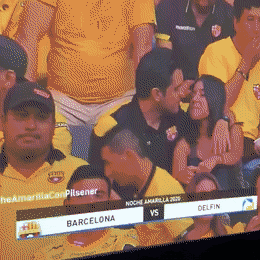 A guy and a girl stop kissing when the cameraman displays their picture on the general screen of the stadium at the Barcelona vs Delfin football match.