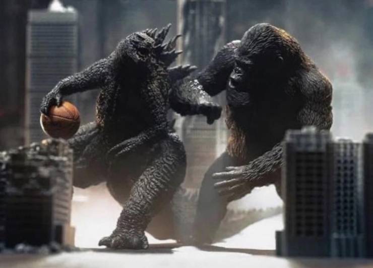 Toy Godzilla and King Kong playing basketball.
