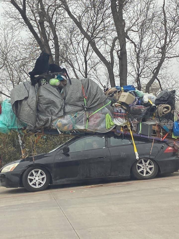 A sports car transporting a huge amount of things on its roof.