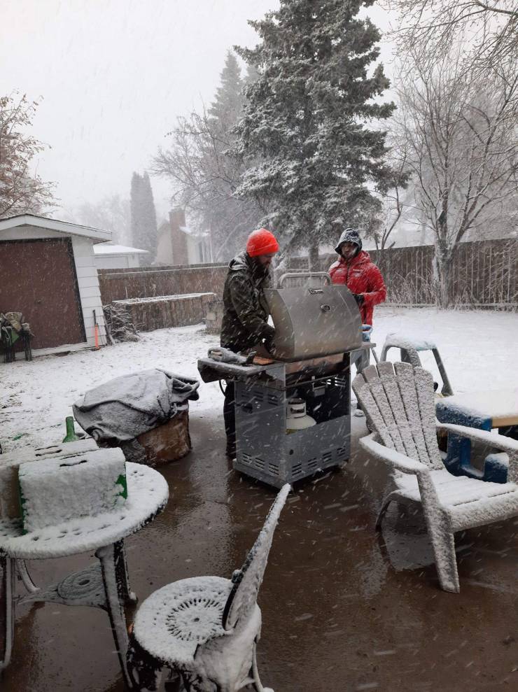 Two men make barbeque in the yard covered with snow.