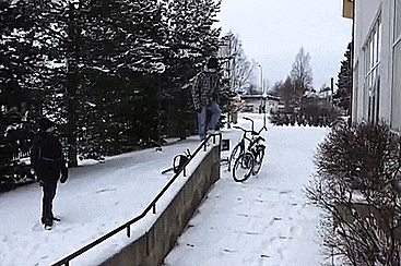 A guy slides down the long stair railings on his feet without falling.
