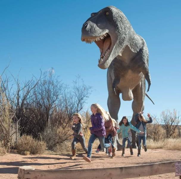 A gigantic dinosaur running after scared kids.