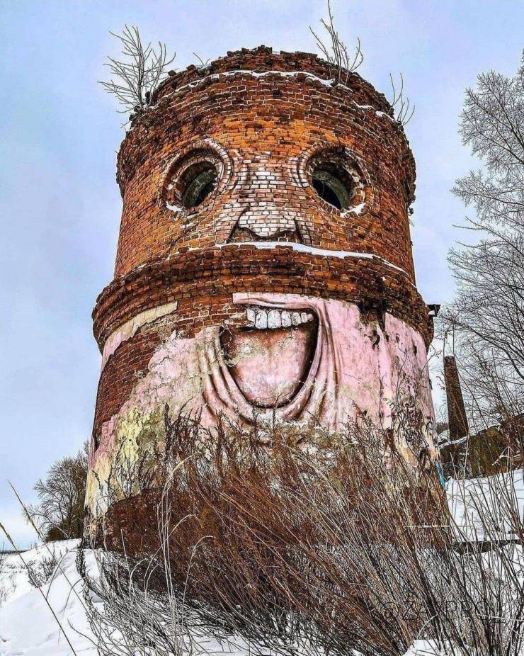 An abandoned brick tower painted like a persons face.