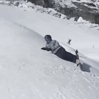 A skier jumps up, high-fives a person lying under him, and keeps riding.