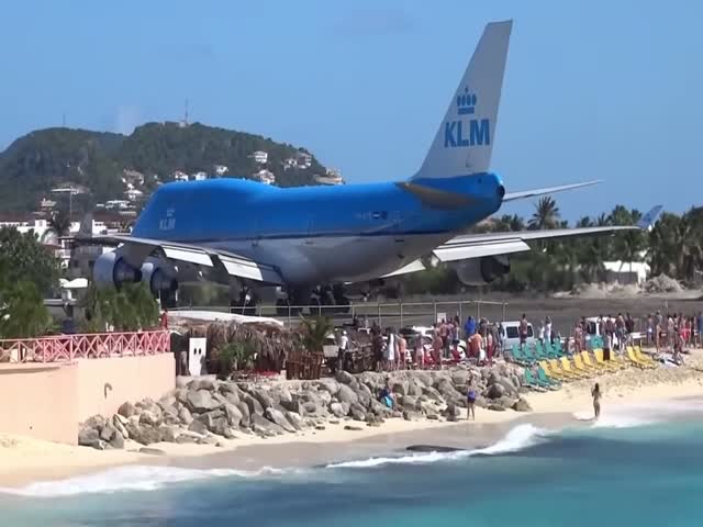 Beachgoers Attempting to Hang Onto a Fence to Withstand the Jet Blast